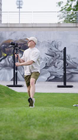 vertical - person with gimbal stabilizer run on green grass lawn, czechia