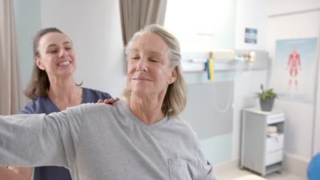 Caucasian-female-physiotherapist-stretching-hand-of-female-senior-patient-at-rehab-center