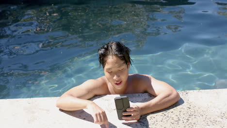 Un-Adolescente-Asiático-Disfruta-De-Un-Día-Soleado-Junto-A-La-Piscina,-Con-Espacio-Para-Copiar