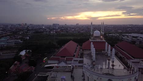 rule of third composition drone shot of the great mosque of central java (majt) in suset time. th sun is orange and the weather is cloudy. it have some pillars and some umbrela that is closed