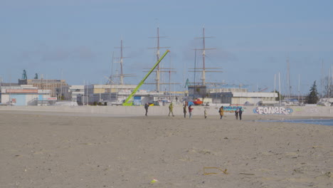 vista lejana de personas con niños caminando por el mar báltico en la playa de arena del centro de gdynia