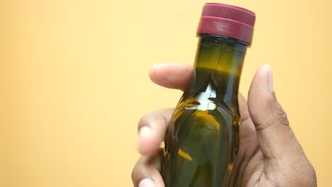 mano sosteniendo una pequeña botella de vidrio verde oscuro con una tapa roja
