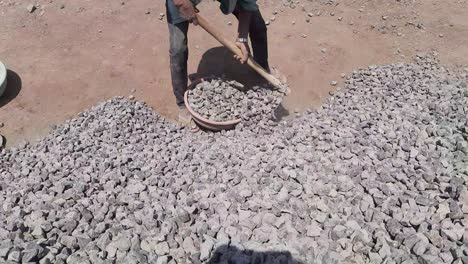 construction worker filling the crusade stone in the iron tasla or ghamela at the construction site