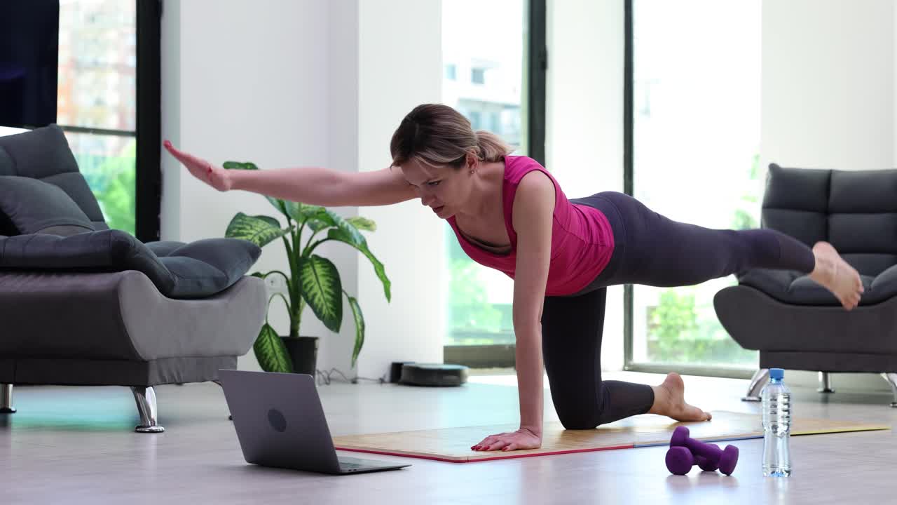 Woman doing home workout with laptop
