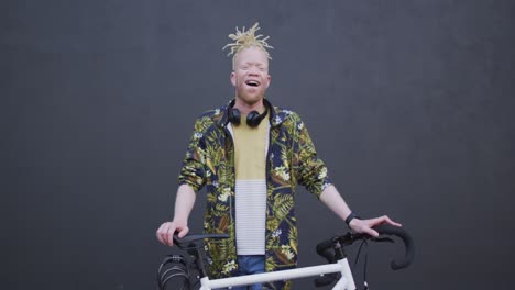 portrait of smiling albino african american man with dreadlocks looking at camera with bike