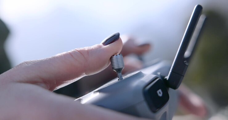 Primo piano delle mani che stringono una vite dell'antenna su un controller di drone all'aperto. Configurazione tecnica per il pilotaggio di UAV