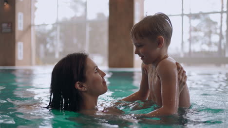 caucasian woman and her little son are having fun in swimming pool preschooler boy is teaching to swim