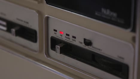 a hand slides an indicator on a wired intercom setup from fm to tape