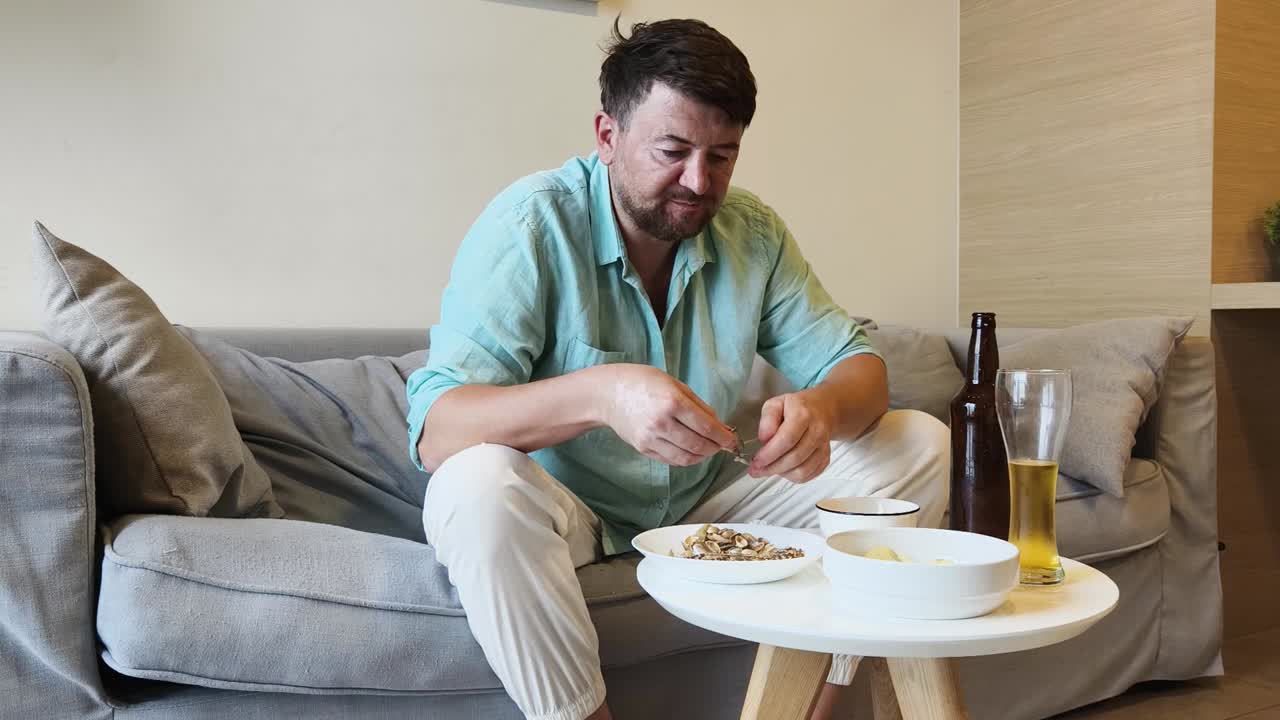Man Relaxing on Sofa with Beer and Snacks