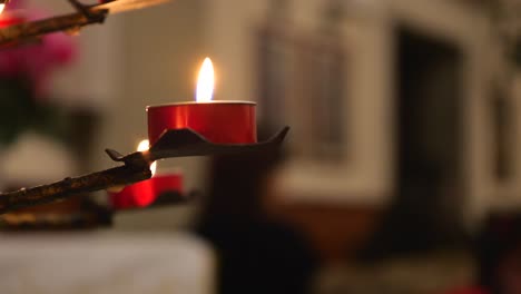lighted candles in red candle holders in church, waving flames