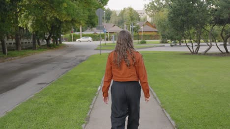 Woman-waving-at-the-camera-saying-goodbye-then-turns-around-and-walks-away,-static