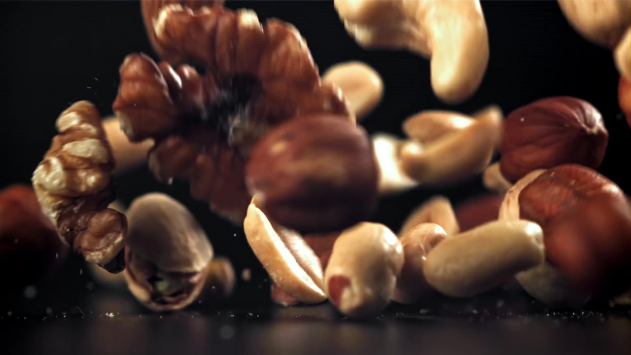 Assortimento di frutta secca salutare che cade al rallentatore su sfondo nero