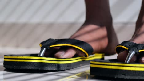 close-up of a person's feet wearing black and yellow slippers