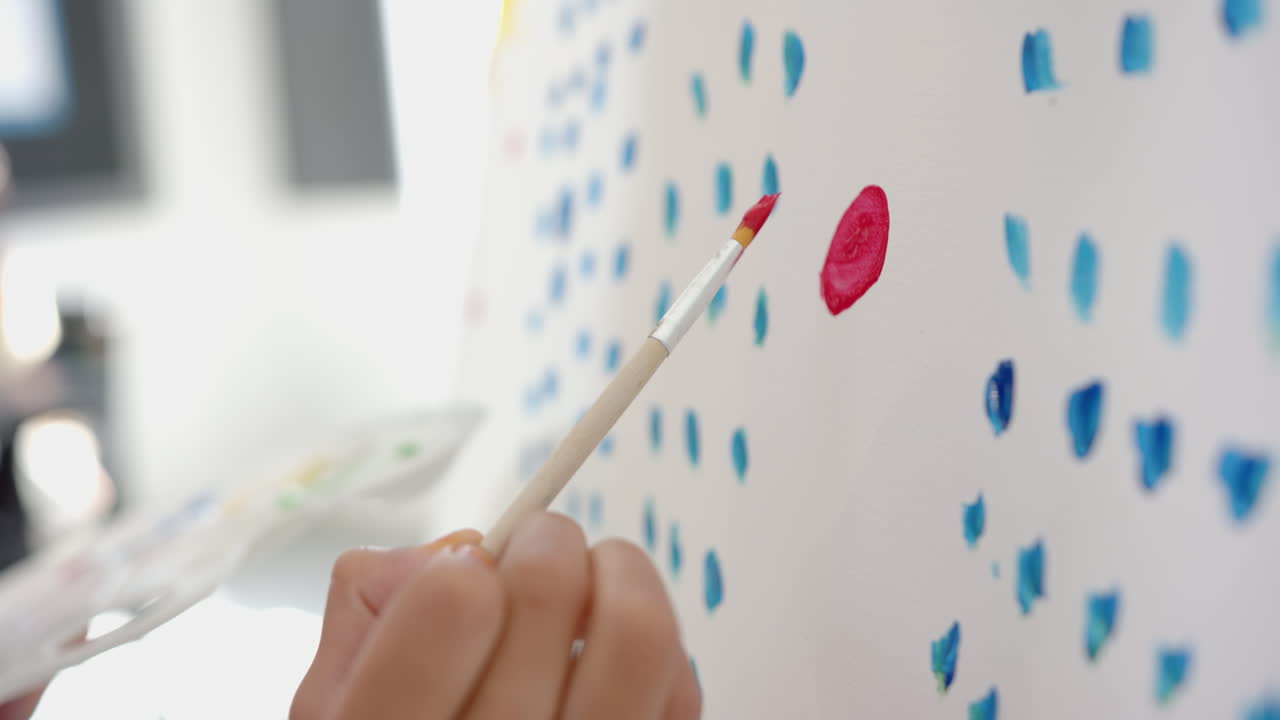 Painting on canvas, student creating colorful artwork in school classroom