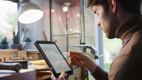 Close-Up-Of-Male-Jeweller-Looking-At-Ring-Design-On-Digital-Tablet-In-Studio