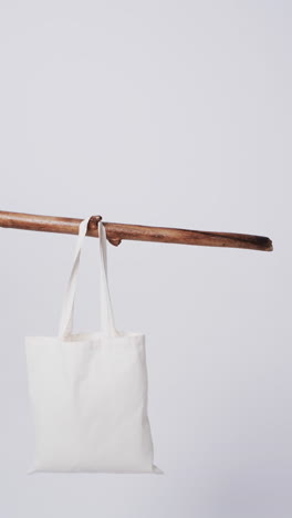 vertical video of white canvas bag hanging from branch with copy space on white background