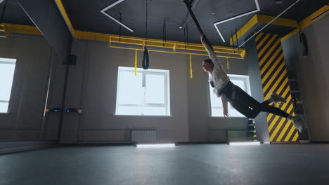 graceful joyful woman is whirling on suspension system in gym enjoying fly over floor sport activity