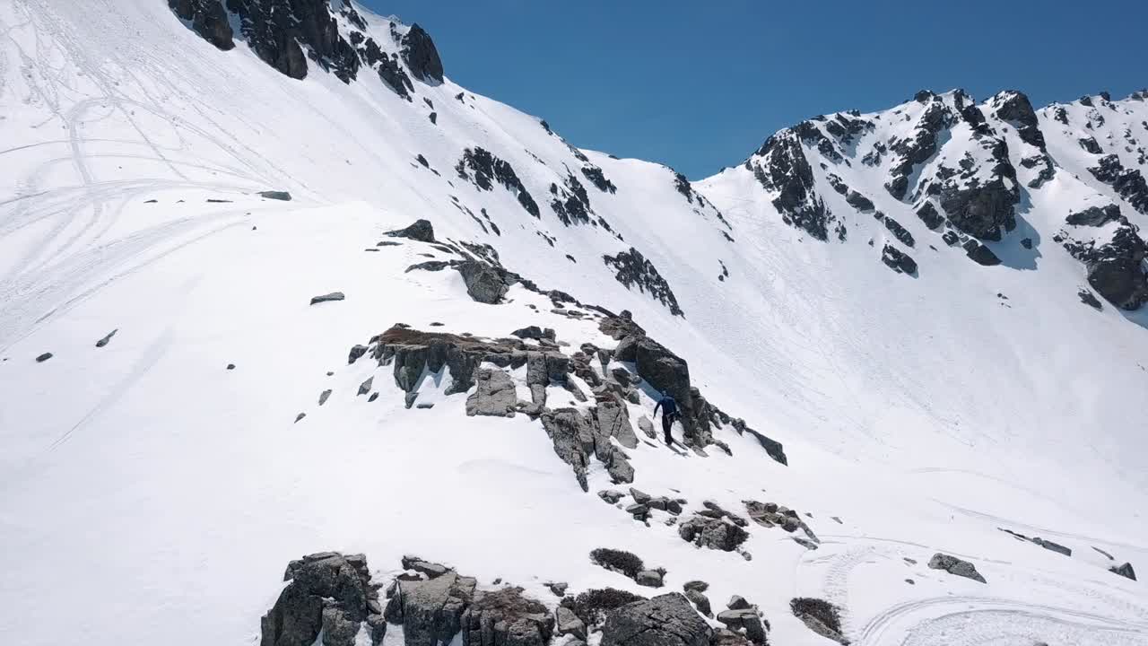 블루버드 데이에 눈 속에서 산을 오르는 남자 스노보더의 공중 전망