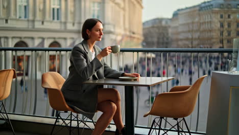 woman drinking coffee on a balcony overlooking the city
