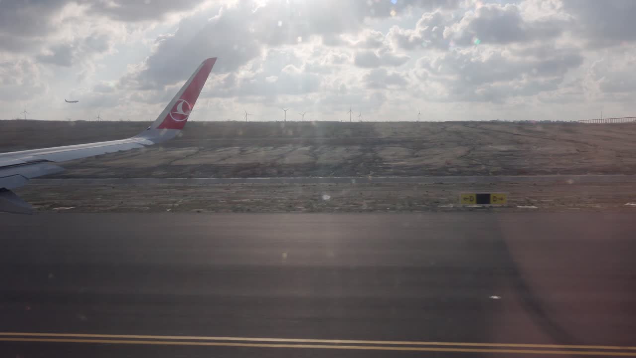 Plane speeding up on a runway preparing for take off on a cloudy day in Istanbul airport. Window view of a plane wing during take off.