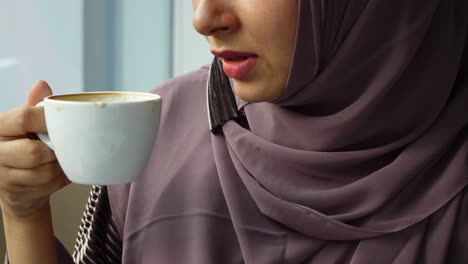 woman in hijab drinking coffee