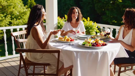 friends enjoying a sunny outdoor brunch with freshly served bread and croissants