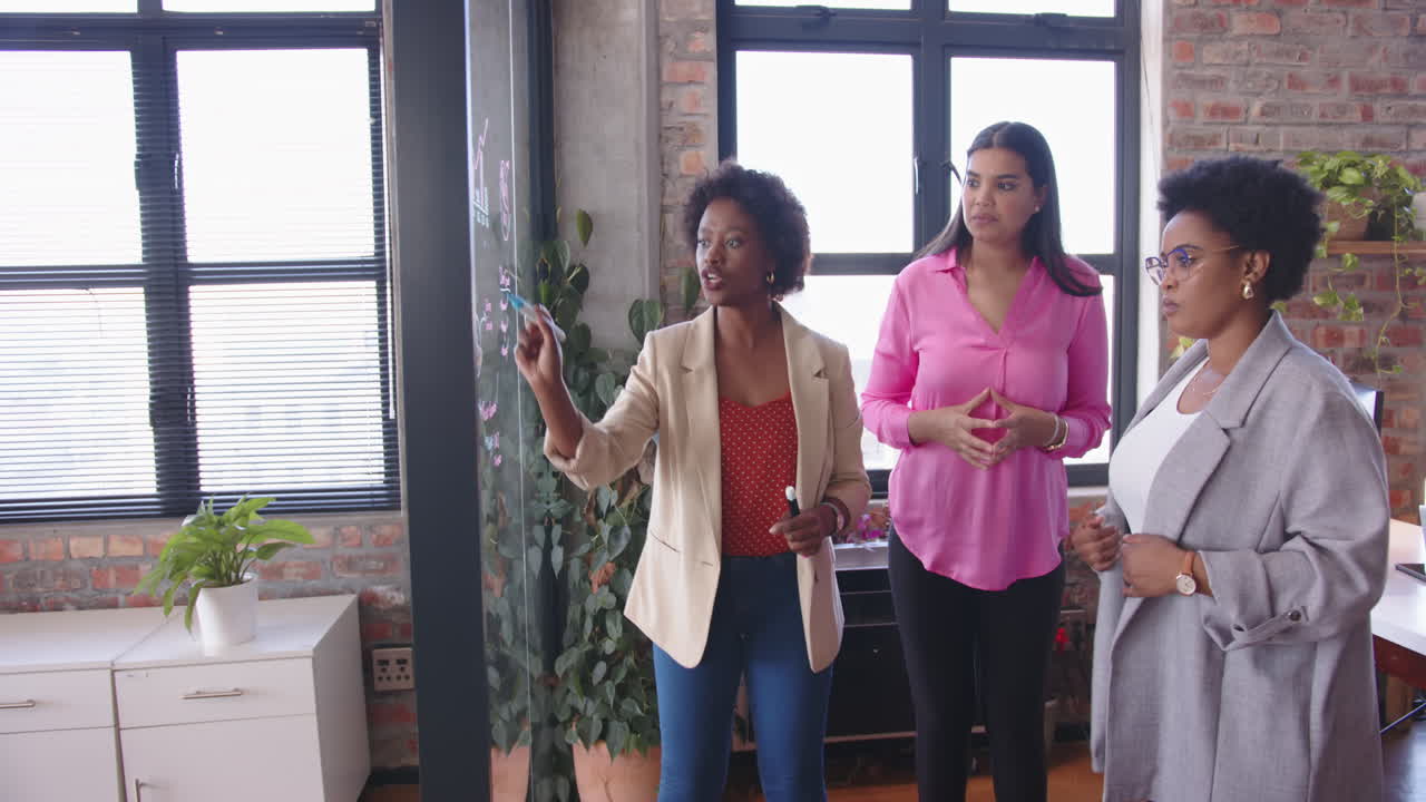 Discussing business strategy, diverse women collaborating in modern office space