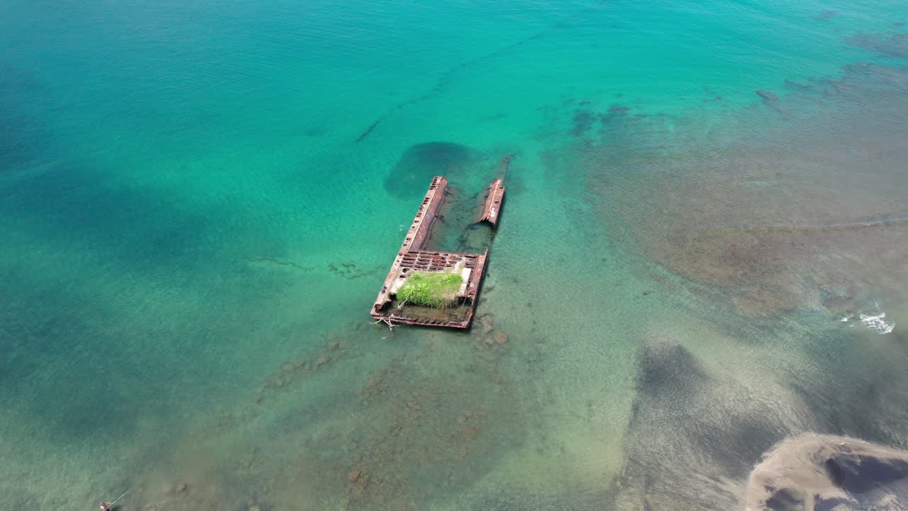Semi orbit drone view capturing the abandoned shipwreck off Puerto Viejo beach, set against the turquoise sea of Costa Rica.