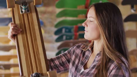 video of happy caucasian female skateboarder in skate shop