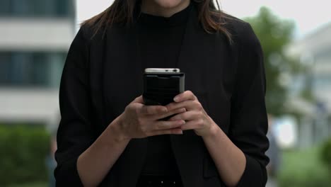 Simple-close-up-view-of-a-young-women-using-her-mobile-device-in-a-clean,-modern-urban-setting