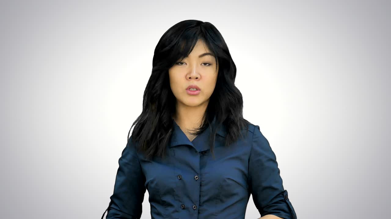 파란색 슈트를 입은 사업가 여성이 색 배경에 제스처로 설명하는 카메라를 보고 미소 짓고 있습니다.