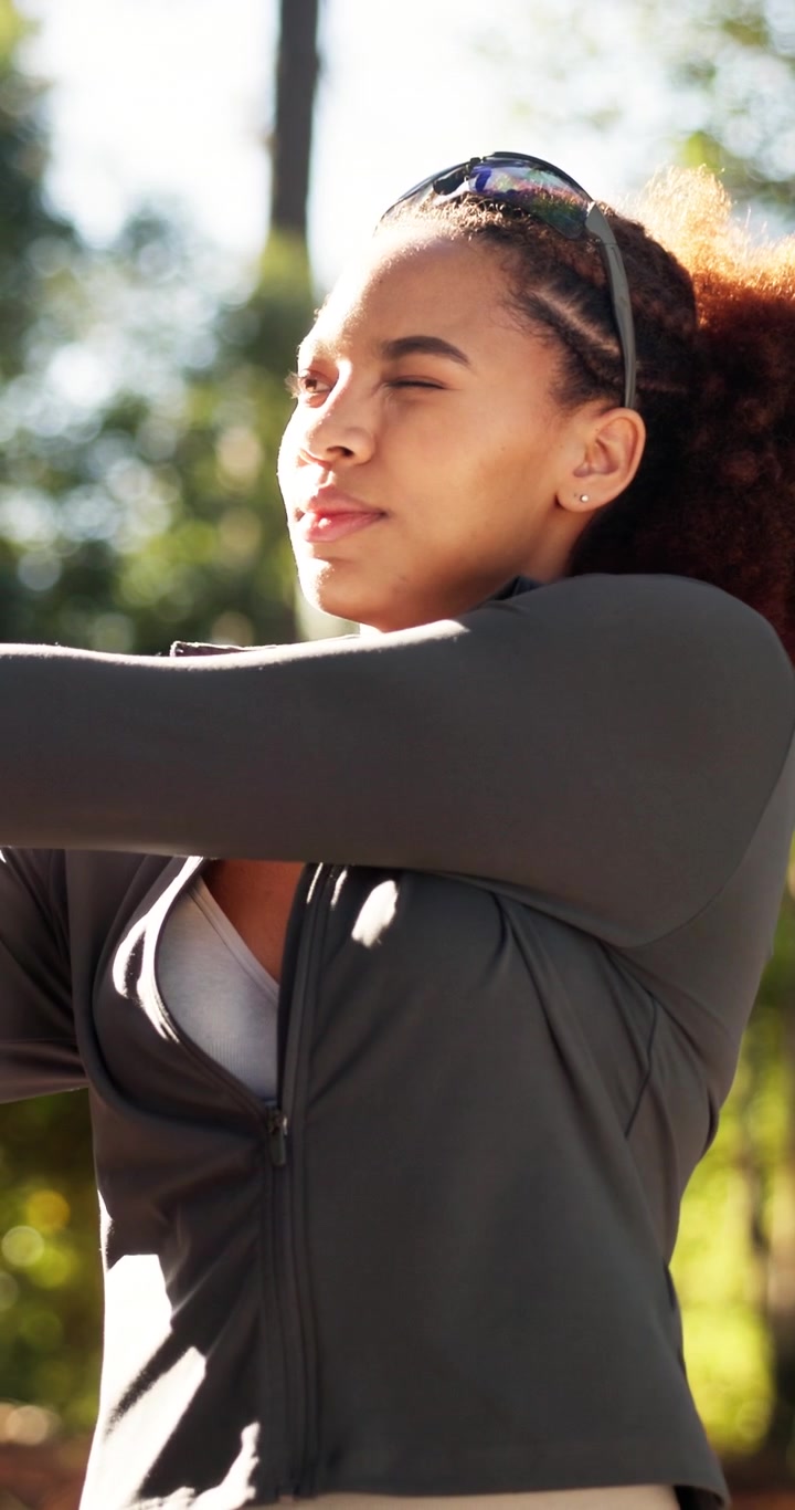 Young Woman Stretching Her Arms Outdoors in a Park