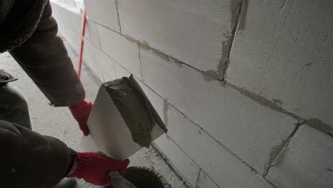 the master performs laying a wall of gas blocks with tools and adhesive mortar