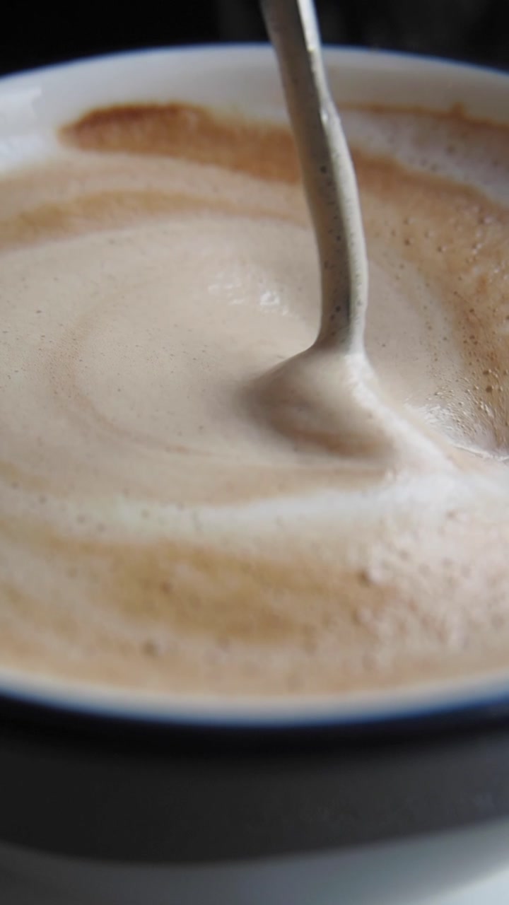 Close-up of Pouring Creamy Milk Foam into a Coffee Latte
