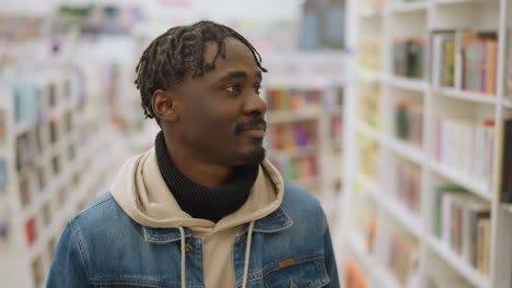 close-up shot of man browsing bookshelves in library or bookstore, focusing on books and deep in thought, exploring literary selections in relaxed indoor setting with ambient lighting