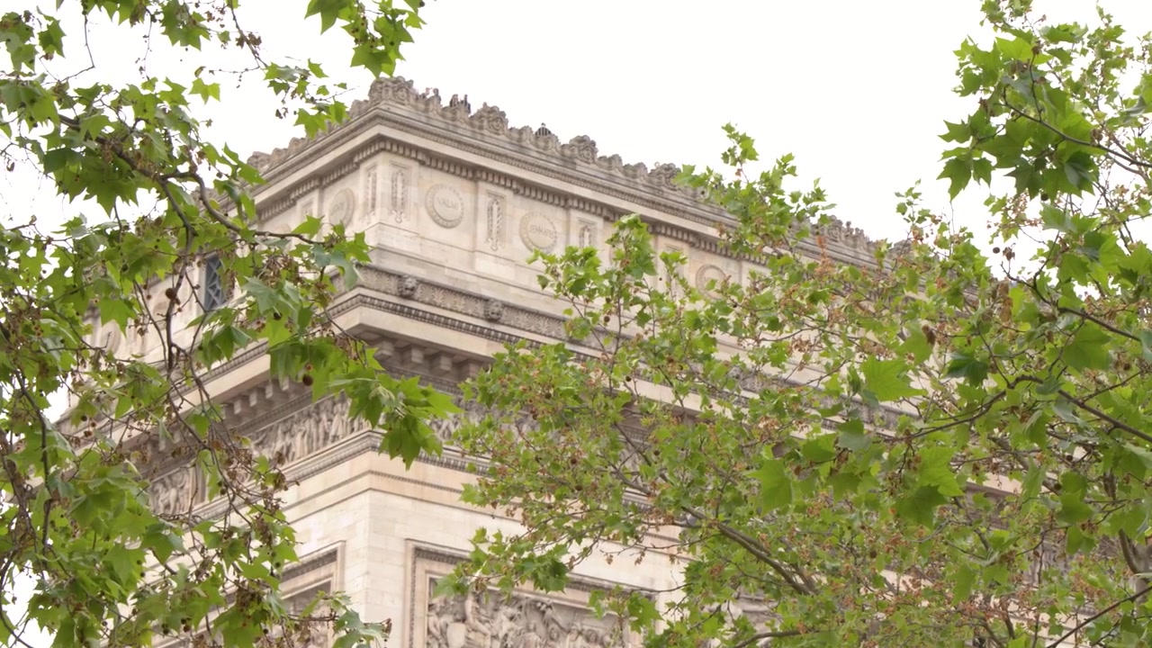Vista de baixo ângulo do Arco do Triunfo através de folhas verdes em Paris, França.
