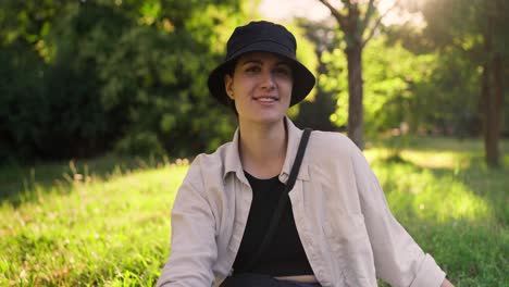 smiling woman sitting on the grass in a park