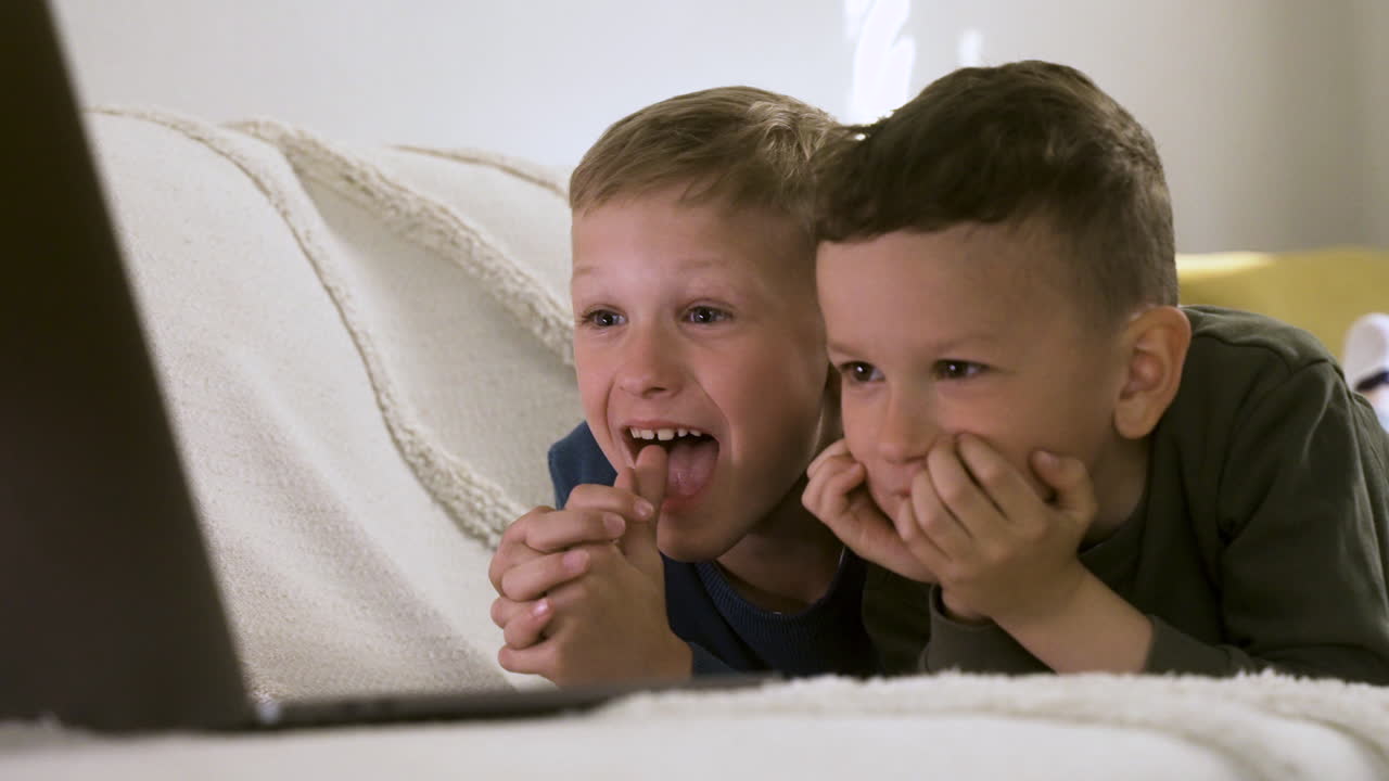 Bambini felici che si godono un film sul divano