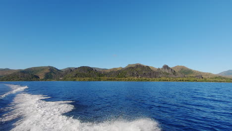 view of tropical island in new caledonia off the back of fast moving boat