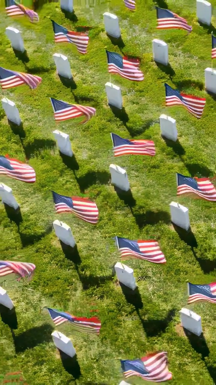 Vertical video: Panning camera showing white headstone rows in cemetery, American flags fluttering