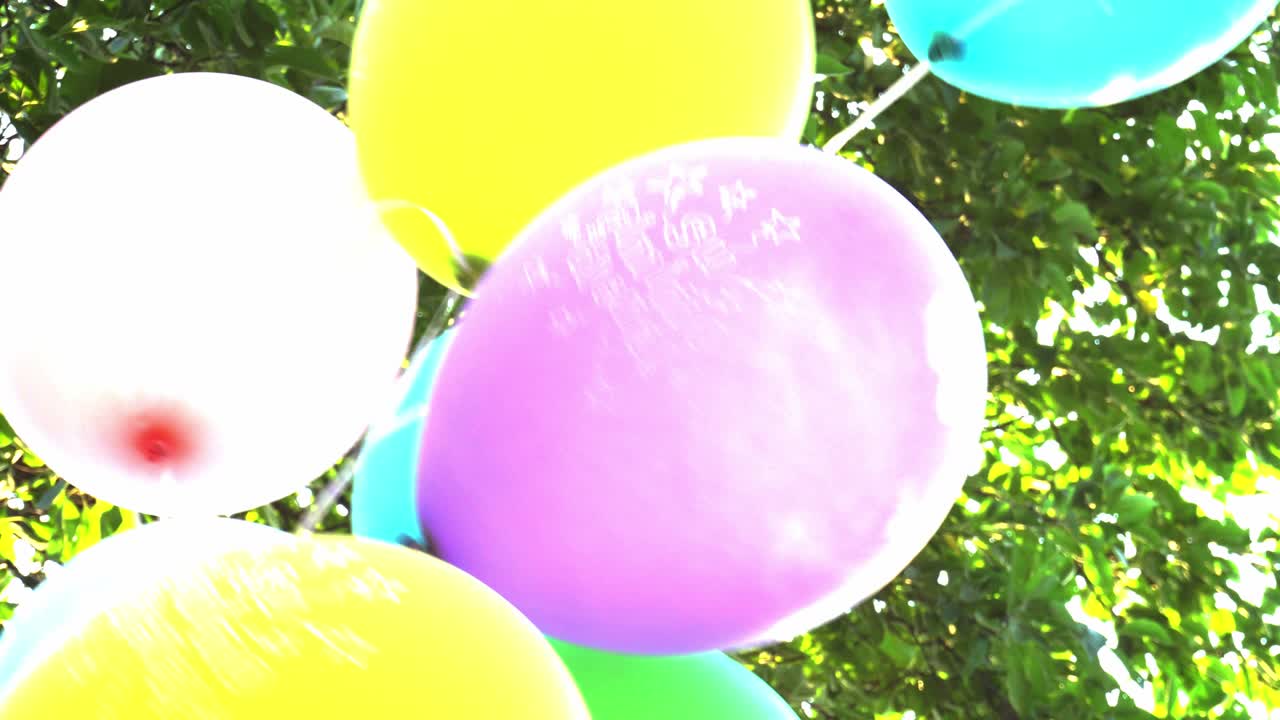 globos. feliz cumpleaños globos de colores se desarrollan en el fondo del cielo y el follaje en cámara lenta.