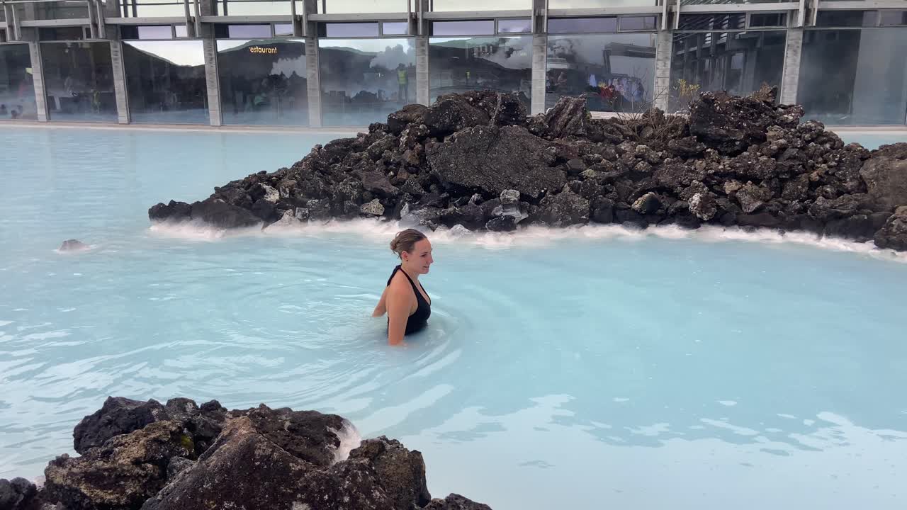 Cheerful sweet young woman happily bathing in Blue lagoon thermal spa in Iceland