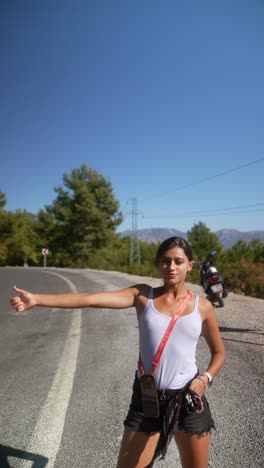 woman hitchhiking on a mountain road