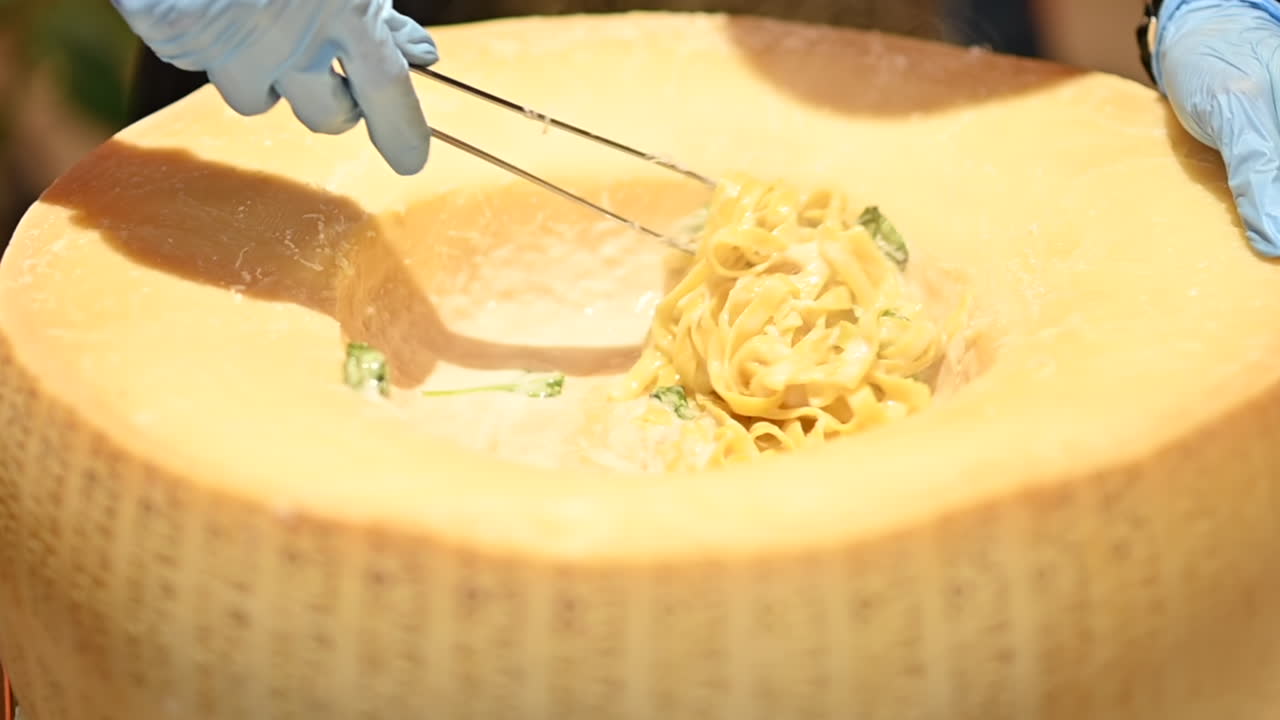 Man mixing pasta in a heated parmesan wheel at a restaurant