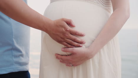 hands of a young man hold hands of his pregnant wife closeup shot