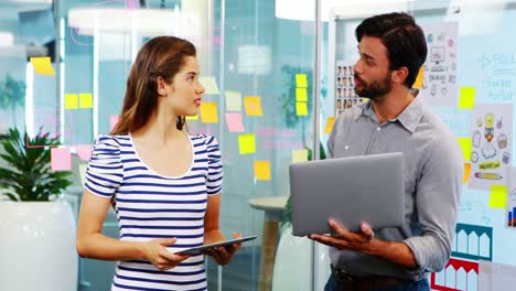 Male-and-female-executives-discussing-over-electronic-devices