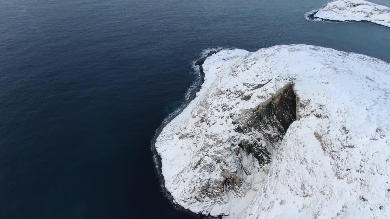 노르웨이의 바다로 둘러싸인 눈 인 산꼭대기 위를 날아다니는 겨울의 트롬소 지역의 드론 뷰