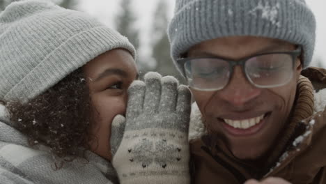 a girl and boy whispering in the snow