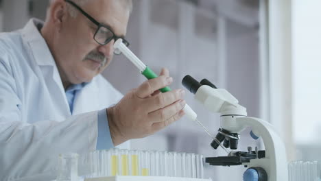 Laboratory.-Hand-in-blue-glove-moves-the-tubes-and-drips-blue-liquid.-Medical-worker-holding-yellow-and-blue-liquid-sample-in-test-tube-analyzing-urine-in-lab.-High-quality-4k-footage