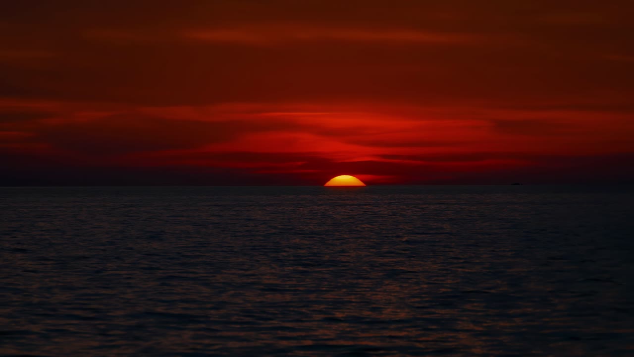 Scenic sunset at Croatian seaside with moving water and glowing sky while sun sinks at the horizon